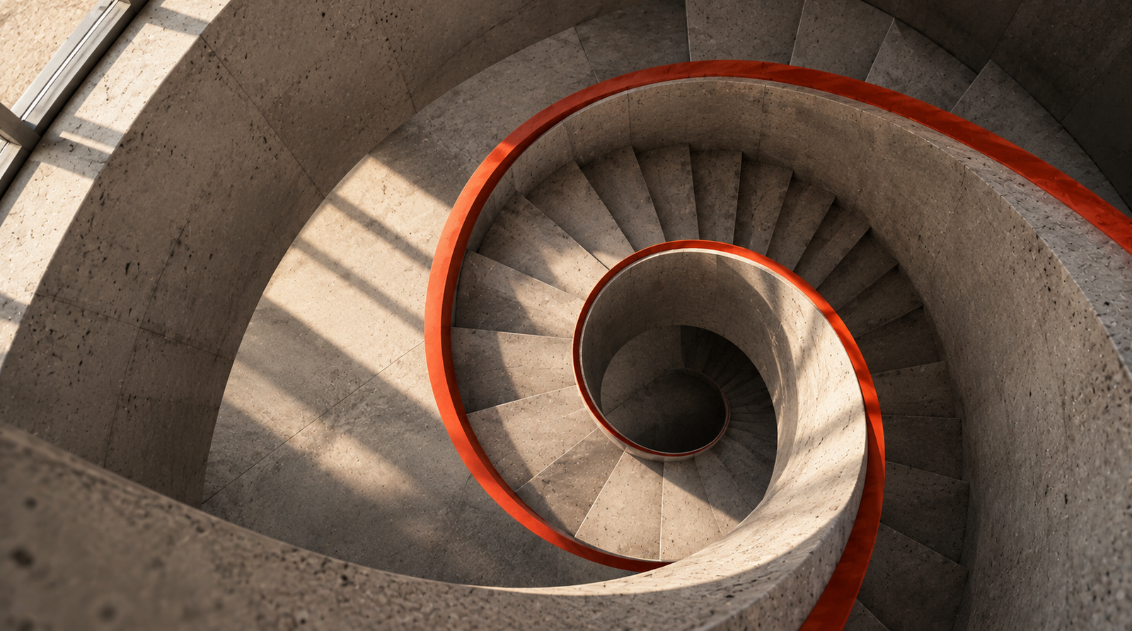 Escalera de hormigón en espiral vista desde arriba con una baranda naranja
